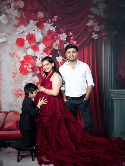A beautiful family moment as an older brother kisses his mother's baby bump, all dressed in coordinated red and black.