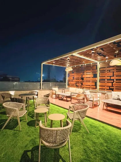We designed this rooftop lounge to be an urban sanctuary. The space combines natural textures like wood decking and an artificial grass lawn with comfortable, modern outdoor furniture. A slatted wood pergola with integrated LED lighting provides both shade and ambiance, creating the perfect setting for relaxation and social gatherings.