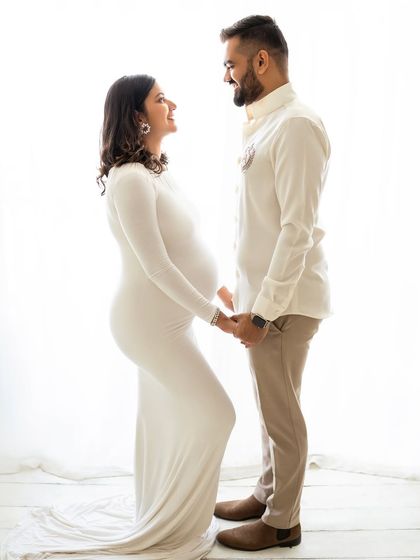 A simple and sweet pose of the couple holding hands and looking at each other. The all-white outfits and bright background keep the focus entirely on their connection.