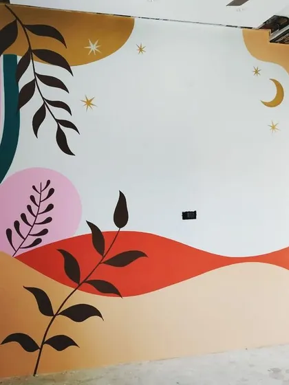 A full view of the abstract botanical mural in progress. This piece combines geometric rainbows with organic leaf shapes, moons, and stars for a whimsical and contemporary feel.