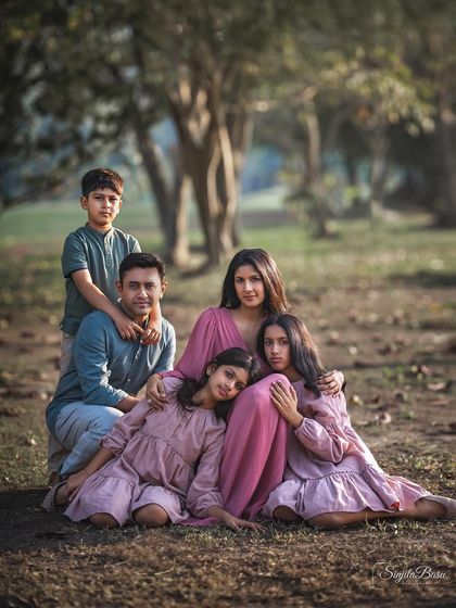 This portrait of a family of five, nestled together outdoors, has the feel of a classic painting. The composition draws you in, showcasing the close-knit bond and the different personalities within the family.