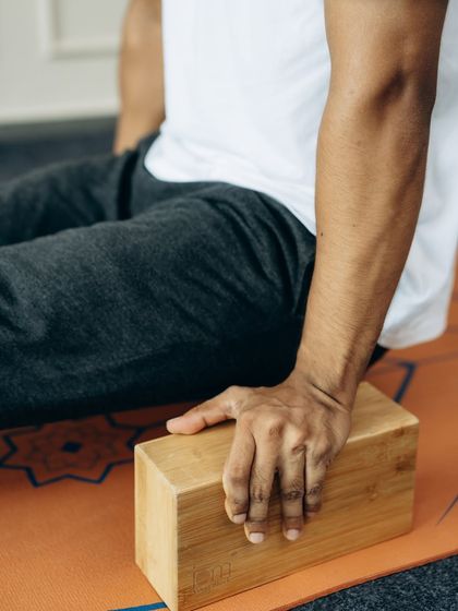 A close-up of a hand gripping a yoga block, ready to support and elevate the practice. Props are an integral part of our teaching methodology.
