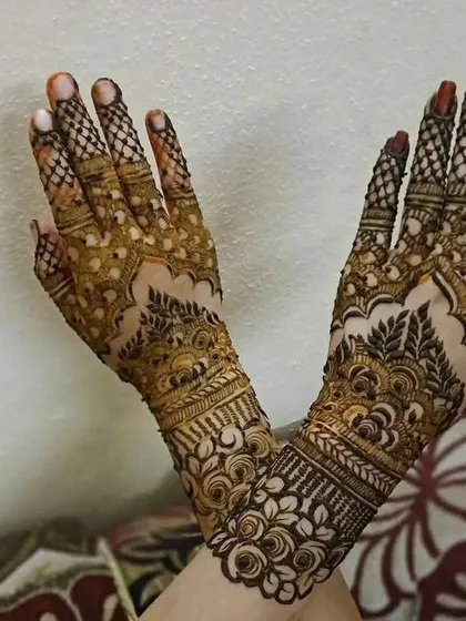 A pair of hands with complementary designs, one featuring a net pattern and the other with more open floral work.