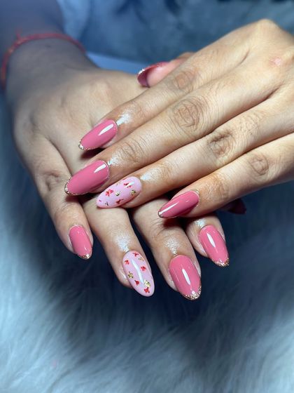 A sweet and simple design with a pink base, gold glitter tips, and a cute accent nail with tiny hearts.