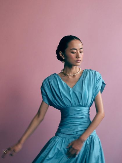 A portrait from the same look, capturing a sense of movement and ease. The focus remains on the pearl necklace and earrings.