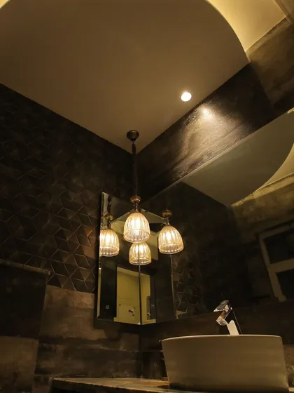 We designed this bathroom with a moody and luxurious atmosphere. Dark, textured walls are paired with a dramatic, curved ceiling cutout with integrated lighting, all centered around an elegant vessel sink.