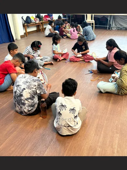 Children sit together in a circle, focused on weaving colorful paper strips into their paper plate baskets. This activity is great for developing fine motor skills and color pattern recognition.