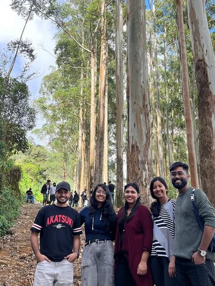 A smaller group of friends posing on the trail inside the pine forest.
