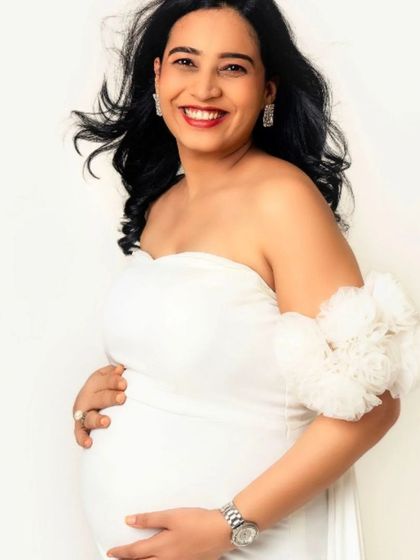 A joyful and radiant portrait of a mom-to-be in our white off-the-shoulder fitted gown.