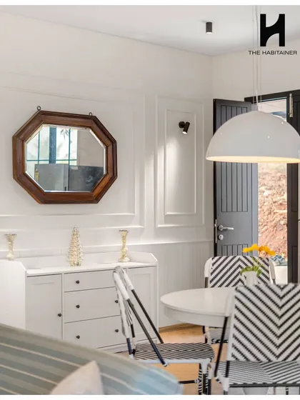 The dining area of the French villa, with its bold chevron-patterned chairs and modern dome pendant light.