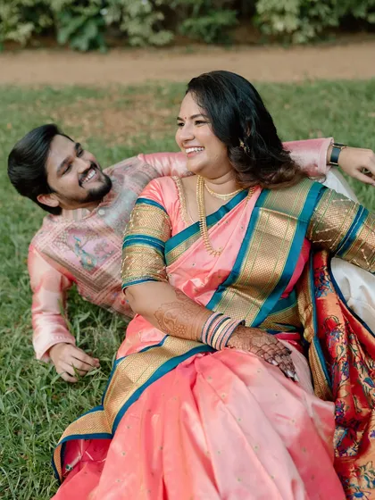 A joyful, candid shot of a couple in traditional Indian attire, laughing together while relaxing on the grass in a lush park. This photo highlights my focus on capturing genuine, unposed happiness during an engagement photoshoot.