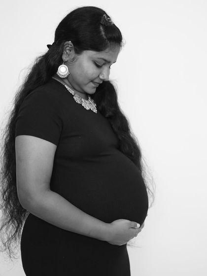 A classic black and white maternity portrait. The simplicity of the pose and monochrome tones create a timeless and artistic image that focuses on the beautiful shape of the baby bump.