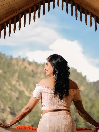 A stunning shot of the bride on a balcony, overlooking the mountains. This image captures the beauty and tranquility of having a destination wedding in a scenic location like Triyuginarayan.