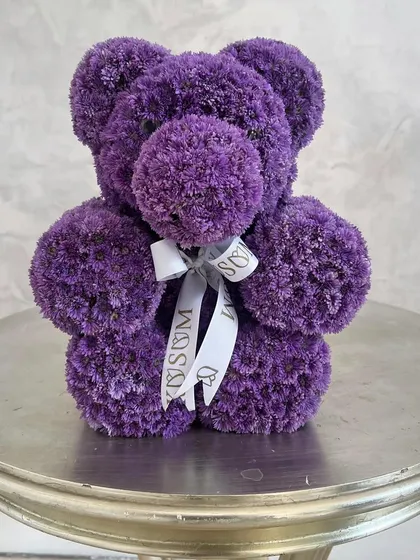 This cuddly purple bear wants to give you a big hug. Made from fresh purple chrysanthemums and finished with our custom ribbon, it's a delightful and unique floral gift for baby announcements or Valentine's Day.
