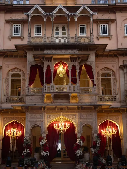 The facade of Chomu Palace, adorned with red drapes and chandeliers, ready for the wedding reception. The lighting design was crucial in transforming the space from day to night.