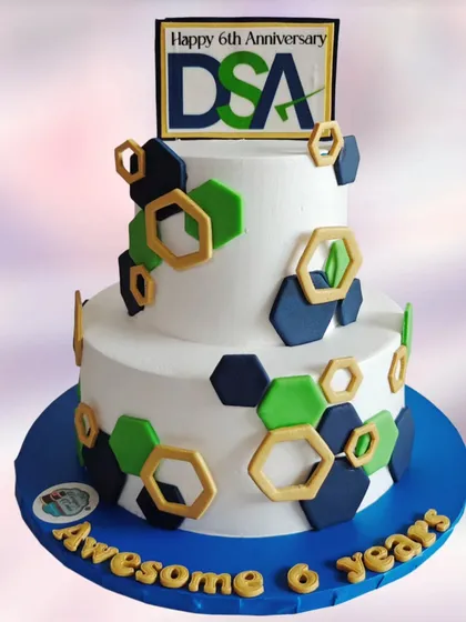 A still shot of the corporate anniversary cake, showing the company logo and a modern hexagonal pattern in the brand's colors.