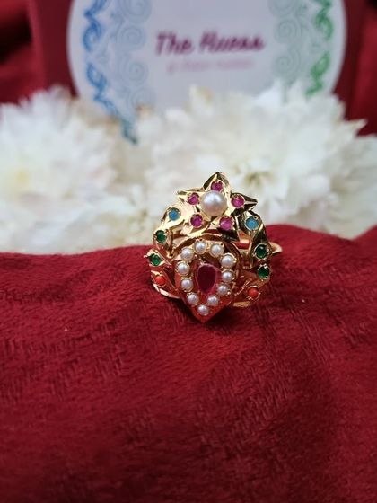 A product shot of the 'रेवा' (Reva) adjustable ring, showcasing its unique shape and vibrant colours.