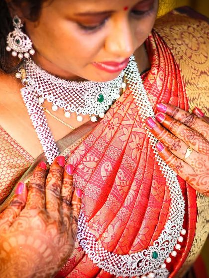 A close-up detail shot of the bride's hands, adorned with henna, against her rich silk saree and diamond jewellery. These shots are perfect for remembering the textures and colours of the day.
