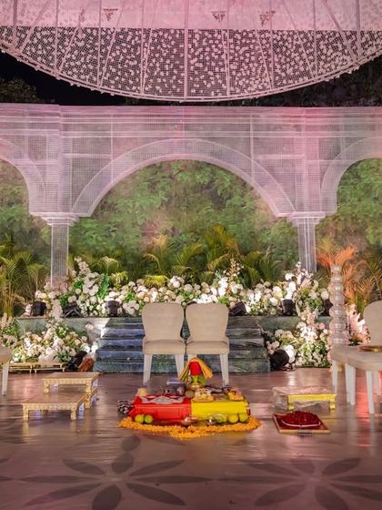 The wedding stage, or mandap, set against a backdrop of lush, living green walls and framed by ethereal white arches. The design feels both grand and intimately connected to nature.