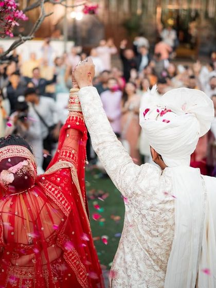 The couple raises their hands in celebration in front of their friends and family. A perfect shot capturing the triumphant feeling of being married.