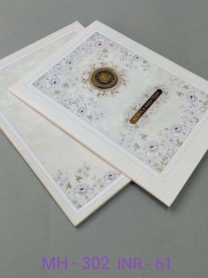 This off-white invitation features a delicate floral pattern and a central nameplate. The design is clean and classic, suitable for any type of celebration.