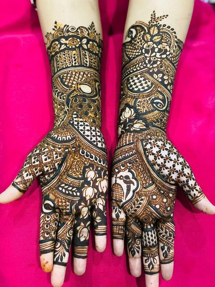 A full view of a traditional henna design, showcasing the flow from the intricate palms to the detailed patterns on the forearms.