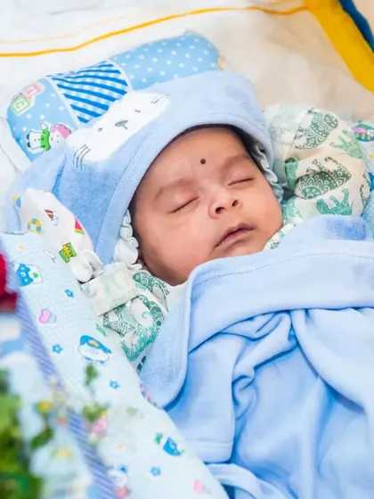 A peaceful photo of a newborn baby sleeping in a decorated cradle during his Naming Ceremony.