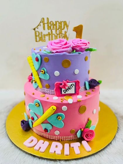 A playful and colorful two-tiered butterfly cake for a first birthday, with bright pink and purple layers and fun butterfly decorations.