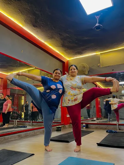 Smiles all around as these two partners master the standing split together. It's a journey of progress, not perfection.
