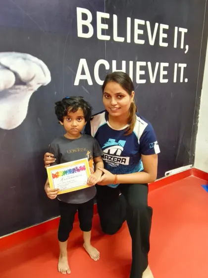"Believe It, Achieve It." This student proudly holds her certificate in front of our motivational wall, a perfect picture of her hard-earned success.