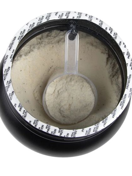 A top-down view into an open tub of whey protein, showing the powder and scoop inside.