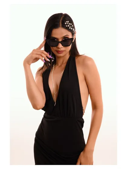 A close-up shot with the model adjusting her sunglasses, creating a classic, movie-star-inspired look.