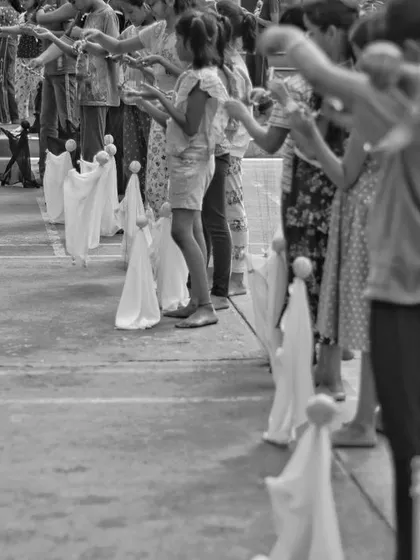 A row of student-made puppets, all pointing forward in unison. This exercise teaches them about coordinated movement and working as a team of performers.