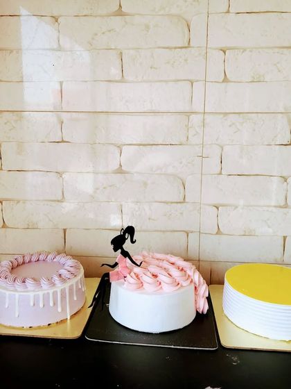 A lineup of cakes waiting to be dressed. This shows the variety of styles we can create, from a simple yellow cake to a pink doll-dress cake.