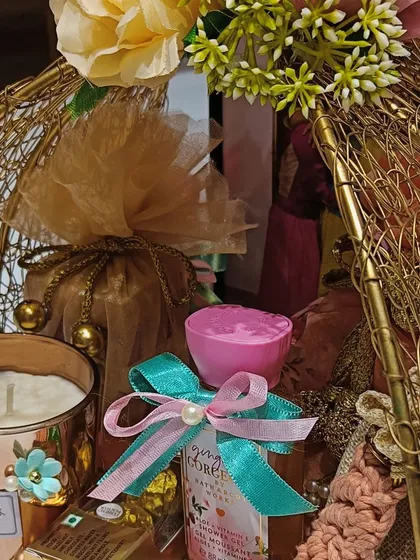 A detailed shot of the scented candle and other small gifts inside the golden wire basket hamper, showing the careful curation of each item.