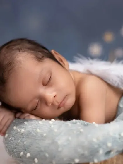 A tiny angel sleeping on a cloud. This newborn portrait features delicate angel wings and a dreamy, starry background, creating a heavenly and serene image.