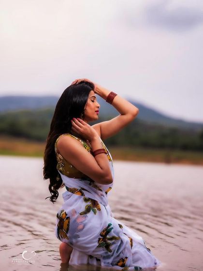 A serene and beautiful portrait of a woman in a floral saree, captured in the water. The reflection and the natural landscape create a truly poetic and artistic image.