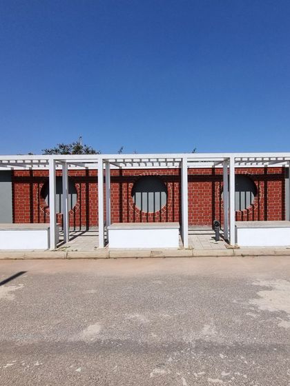 A straight-on view of the completed pergola and seating structures at the Aamby City entrance, ready for planting.