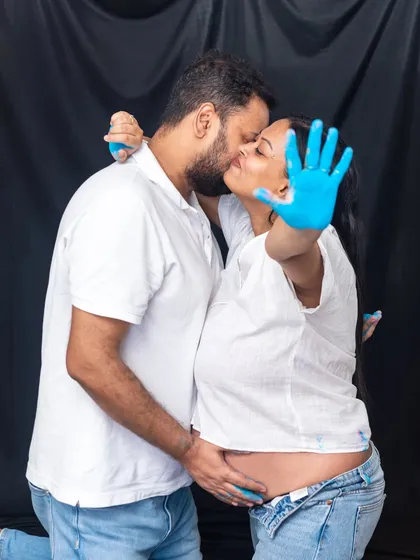 A fun and messy gender reveal. This couple's kiss is captured amidst a splash of blue paint, a creative and memorable way to announce "it's a boy."