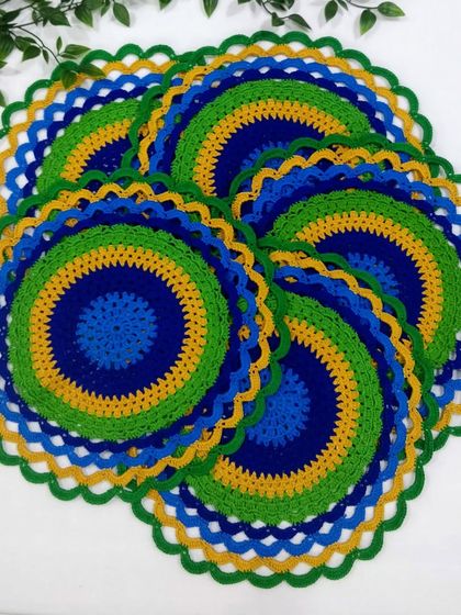 A set of six peacock placemats spread out, showing how they look as a complete dining set. The colors are so lively and eye-catching.