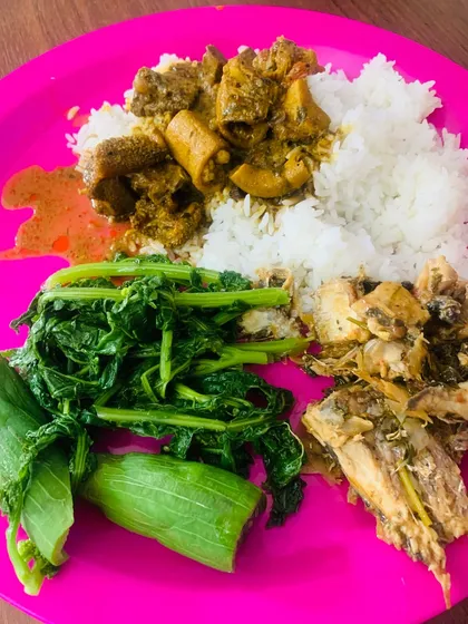 A vibrant thali with beef curry, fish, boiled greens, and rice. A perfect combination of flavors.