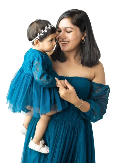 A beautiful mother-daughter portrait against a clean white studio background. The matching teal dresses and the gentle interaction between them create a truly special image.