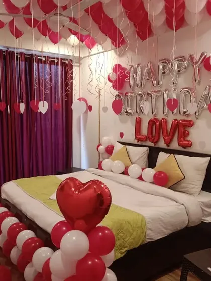 Another view of the red and white romantic room setup, showing balloon pillars with heart foil toppers.