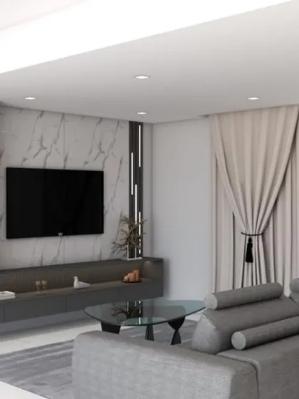 A contemporary family TV room featuring a full-wall entertainment unit with integrated shelving and storage. The dark grey tones and marble-effect back panel create a sophisticated and cinematic feel.