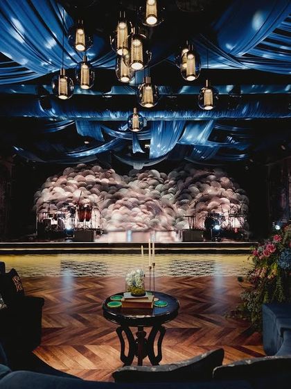 For the 'Midnight Mirage' sangeet in Bali, I transformed a plain banquet hall into a mystic forest. The design was inspired by the deep hues of cobalt blue, with custom floral wallpaper, dramatic ceiling drapes, and a stage backdrop made of thousands of handmade paper fans.
