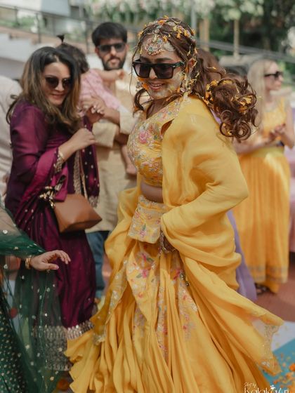A bride dances with joy during her Haldi ceremony, her yellow lehenga flowing around her. We capture the movement and energy of the day.