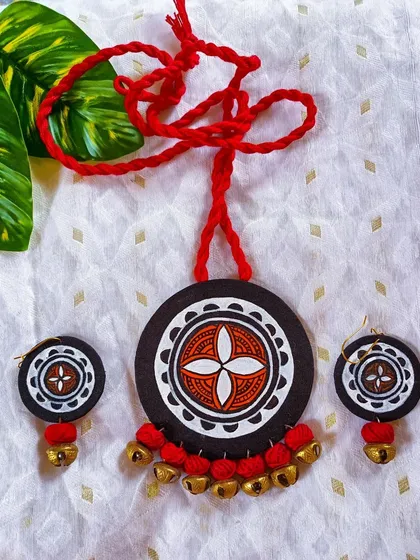 A well-composed shot of the red and black mandala pendant with ghungroos, showcasing the crispness of the hand-painted white lines.