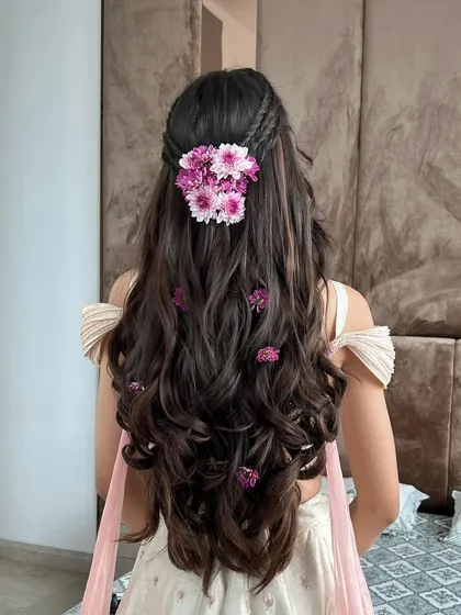 A closer look at the back of the floral half-updo, showing the cluster of flowers at the crown and smaller ones scattered through the curls.