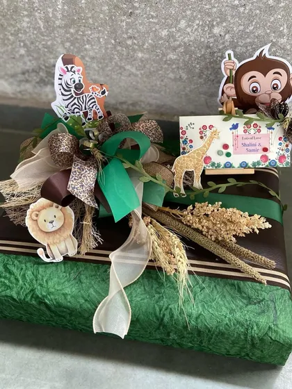 A wild adventure awaits! This jungle-themed gift box is wrapped in green textured paper and decorated with cute animal cutouts, perfect for a baby boy's shower or birth announcement.