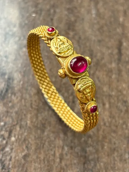The same stunning gold-plated silver kada, this time with a beautiful ruby-red central stone. The temple coin motifs add a touch of traditional heritage to this elegant piece.